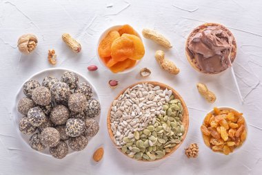 Doğal sağlıklı çiğ enerji ısırıkları, çikolata ezmesi ve beyaz bir masada fındıklı kurutulmuş meyve karışımı. Üst görünüm