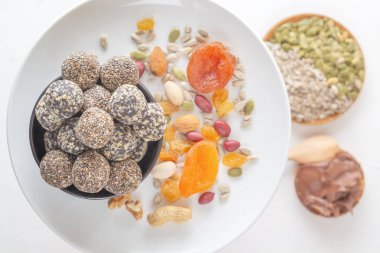 Doğal sağlıklı çiğ enerji ısırıkları ve beyaz bir tabakta kurutulmuş meyve ve fındık karışımı. Üst Manzara. Yakın plan.