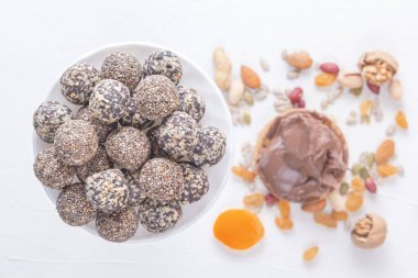 Doğal sağlıklı çiğ enerji ısırıkları, çikolata ezmesi ve beyaz bir masada fındıklı kurutulmuş meyve karışımı. Üst görünüm