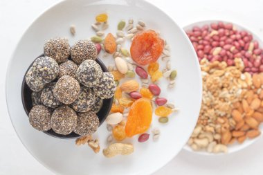 Doğal sağlıklı çiğ enerji ısırıkları ve beyaz bir tabakta kurutulmuş meyve ve fındık karışımı. Üst Manzara. Yakın plan.