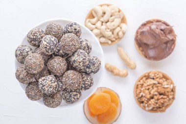 Doğal sağlıklı çiğ enerji ısırıkları, çikolata ezmesi ve beyaz bir masada fındıklı kurutulmuş meyve karışımı. Üst görünüm