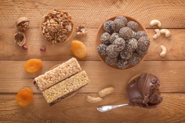 Doğal sağlıklı çiğ enerji ısırıkları, çikolata ezmesi ve kurutulmuş meyve karışımı karanlık bir masada fındık. Üst görünüm