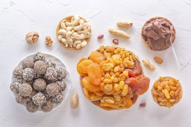 Doğal sağlıklı çiğ enerji ısırıkları, çikolata ezmesi ve beyaz bir masada fındıklı kurutulmuş meyve karışımı. Üst görünüm