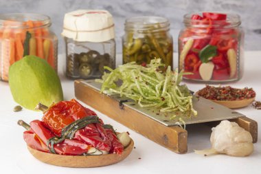 Baharat ve turpla bağışıklığı arttırmak için mayalanmış kırmızı biber hafif bir ahşap masada rendelenmiş bir el rendesi ile cam kavanozların ve turşu ürünlerinin arka planına karşı