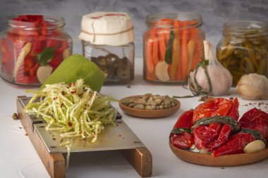 Farklı ürünlerin arka planında rendelenmiş turp. Biber, sarımsak, havuç, açık ahşap bir masa.