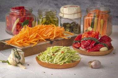 Farklı ürünlerin arka planında rendelenmiş turp. Biber, sarımsak, havuç, açık ahşap bir masa.