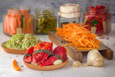 Baharatlarla bağışıklığı arttırmak için mayalanmış kırmızı biberler ve hafif ahşap bir masada rendelenmiş havuçlar ile turşulu cam kavanozların arka planına karşı.