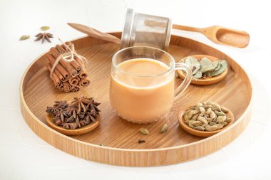 Cam bardakta Masala çayı ve hazırlanması için doğal bir karışım - yıldız anason, tarçın çubukları, kakule, defne yaprağı, ahşap tabakta biber ve biber