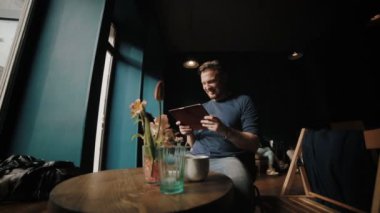 Genç adam bir dinlenme kafeteryada ve haber okur