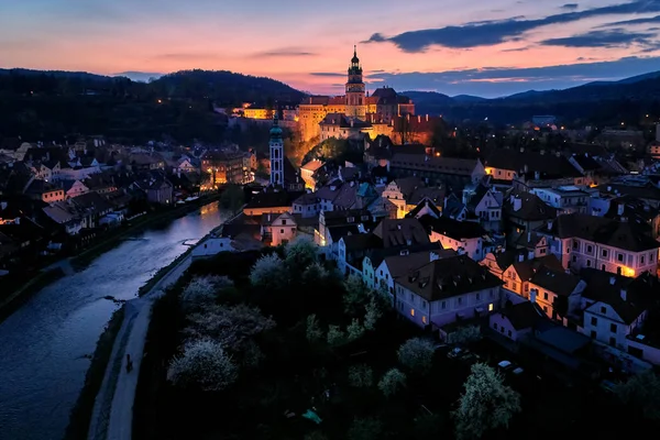 Vue aérienne en soirée sur une ville de l'Unesco, Cesky Krumlov, perle de l'architecture de la Renaissance au-dessus d'une rivière Vltava. Vue sur le crépuscule, ville éclairée par des lampes orange contre des ombres bleues. Paysage tchèque . — Photo