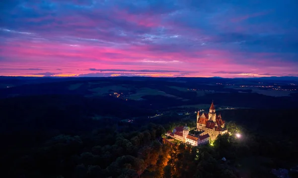 Noche, vista aérea en el castillo iluminado brillante Bouzov en la colina contra el atardecer rojo — Foto de Stock