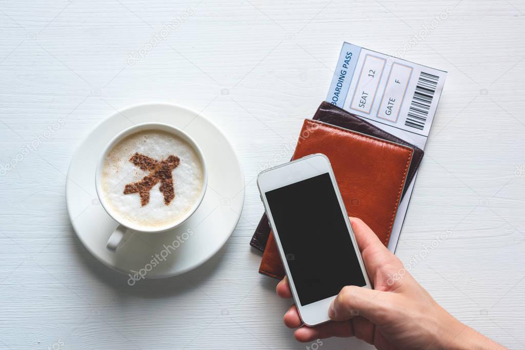 Airplane made of cinnamon in coffee,  white smartphone, passport and boarding pass