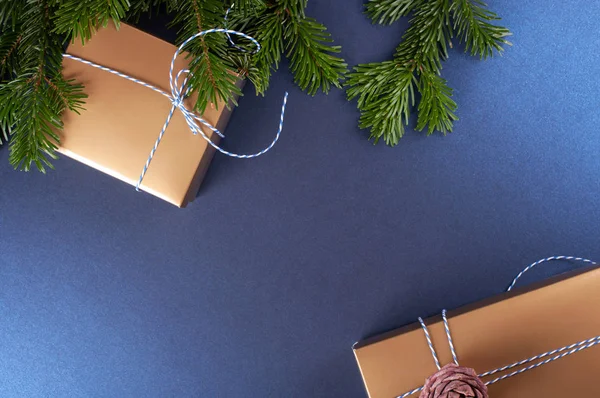 Çam ağacı dallarının yanında altın hediye kutusu