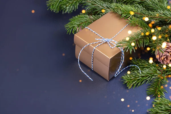 Çam ağacı dallarının yanında altın hediye kutusu