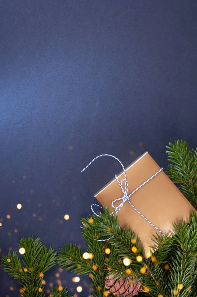 Çam ağacı dallarının yanında altın hediye kutusu