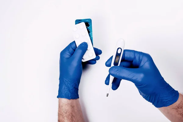 Adam termometre ve ilaç haplarını tutuyor.