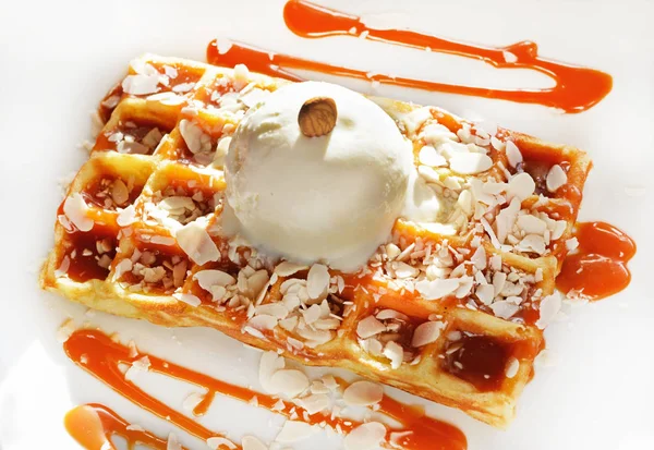 Belgian waffle with  ball of vanilla ice cream, caramel syrup and almonds