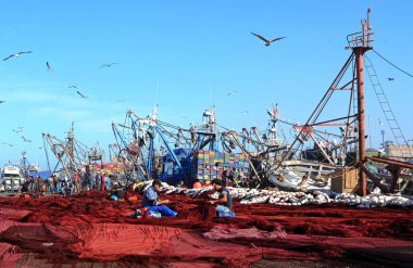 Essaouira, Fas - 5 Ocak 2016: zemin ve dikiş ağlar üzerinde yayılan kırmızı balık ağlarına th ortasında oturan iki insanlar