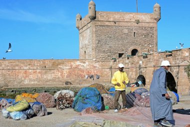 Essaouira, Fas - 5 Ocak 2016: Balıkçı tekneleri, dişli ve balıkçılar Mogador Castelo gerçek arka plan üzerinde.
