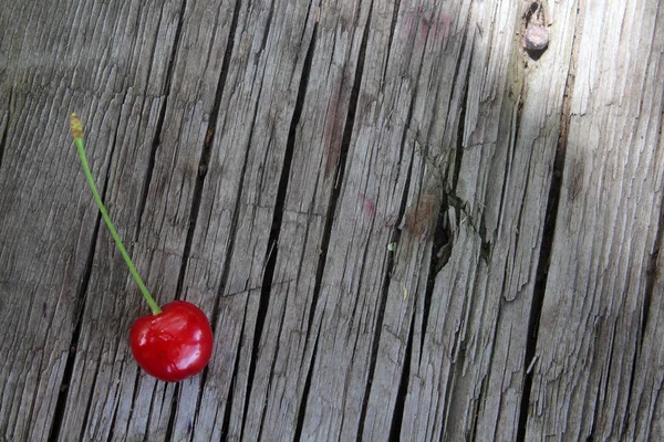 Eine reife rote Kirsche auf einem alten Tisch — Stockfoto