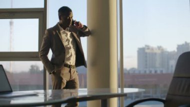 Genç işadamı güneş ofiste penceresinde smartphone ayakta kullanarak takım siyah