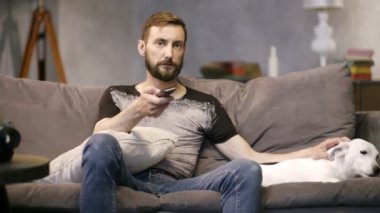 Sakallı adam televizyon konsol ve köpekleri kullanarak kanepede oturan