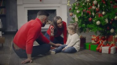 Annem ve babam arka plan Noel ağacı ve mevcut kutusu kızı ile oynamaya