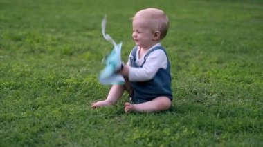 Portre çayır üzerinde oturan ve holding küçük kız eller panama şapka