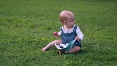 Yaz çayır, yeşil çimenlerin üzerinde oturan gülümseyen bebek kız