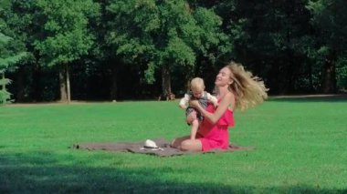 Genç anne bebekle yeşil çayır on yaz günü içinde oynamaya.