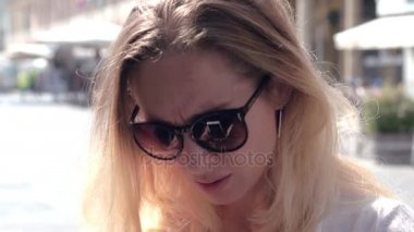 Şehir sokak üzerinde mesaj yazmak için telefon kullanarak güneş gözlüğü güzel kadın