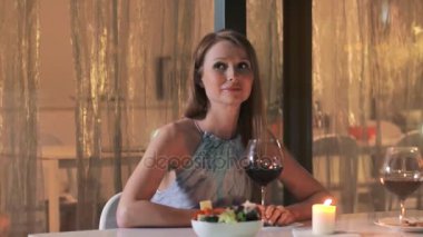 Restoranda akşam yemeği masada oturan ve kırmızı şarap içme güzel kadın