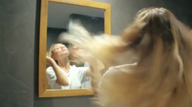 Sarışın kadın ile uzun saç sallayarak ve banyo aynaya bakarak