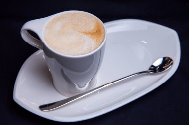 Latte bir restaurantında beyaz uzun plaka üzerinde beyaz Kupası'nda uzun latte kaşıkla besleme kahve fincan 