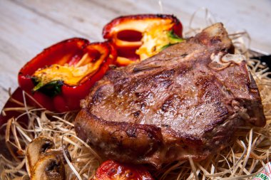 Domuz eti sığır eti biftek ızgara biber, domates ve Tabasco sos plaka saman şeklinde dekor ve biftek için bir bıçak ile ızgara, mantar ile