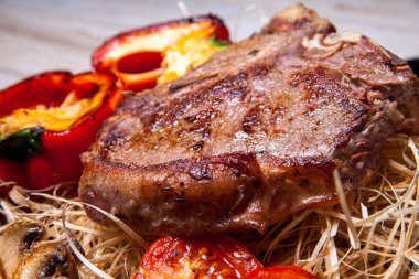 Domuz eti sığır eti biftek ızgara biber, domates ve Tabasco sos plaka saman şeklinde dekor ve biftek için bir bıçak ile ızgara, mantar ile