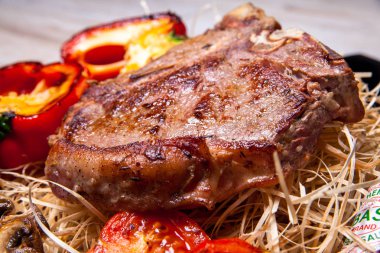 Domuz eti sığır eti biftek ızgara biber, domates ve Tabasco sos plaka saman şeklinde dekor ve biftek için bir bıçak ile ızgara, mantar ile