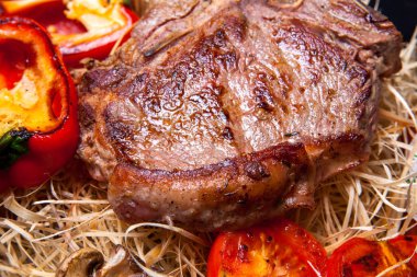 Domuz eti sığır eti biftek ızgara biber, domates ve Tabasco sos plaka saman şeklinde dekor ve biftek için bir bıçak ile ızgara, mantar ile