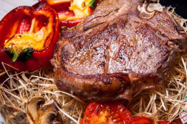 Domuz eti sığır eti biftek ızgara biber, domates ve Tabasco sos plaka saman şeklinde dekor ve biftek için bir bıçak ile ızgara, mantar ile