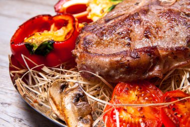 Domuz eti sığır eti biftek ızgara biber, domates ve Tabasco sos plaka saman şeklinde dekor ve biftek için bir bıçak ile ızgara, mantar ile