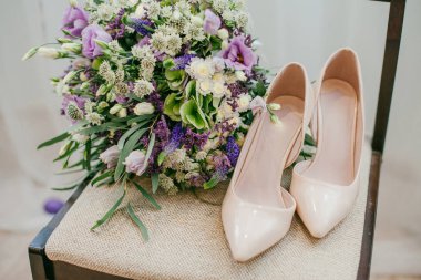 Büyük mor düğün buketi ve gelinin sandalye üzerinde bej ayakkabı bileşimi