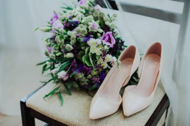 Büyük mor düğün buketi ve gelinin sandalye üzerinde bej ayakkabı bileşimi