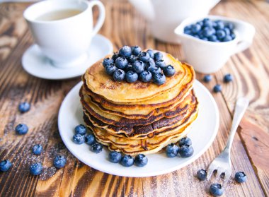 Yaban mersini, bataklık whortleberry, yeşil çay, yaban mersini ve çaydanlık kahverengi ahşap zemin üzerinde kupa ile sağlıklı kahvaltı krep 