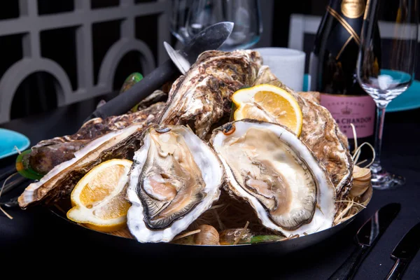 Öppnade ostron på Folkmusik inredda plattan med citron och oyster kniv i restaurang utfodring med ros champagne — Stockfoto