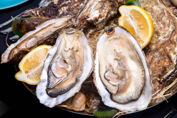 Öppnade ostron på Folkmusik inredda plattan med citron och oyster kniv i restaurang utfodring med ros champagne — Stockfoto