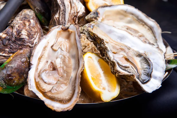 Öppnade ostron på Folkmusik inredda plattan med citron och oyster kniv i restaurang utfodring med ros champagne — Stockfoto