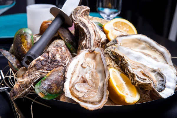 Öppnade ostron på Folkmusik inredda plattan med citron och oyster kniv i restaurang utfodring med ros champagne — Stockfoto