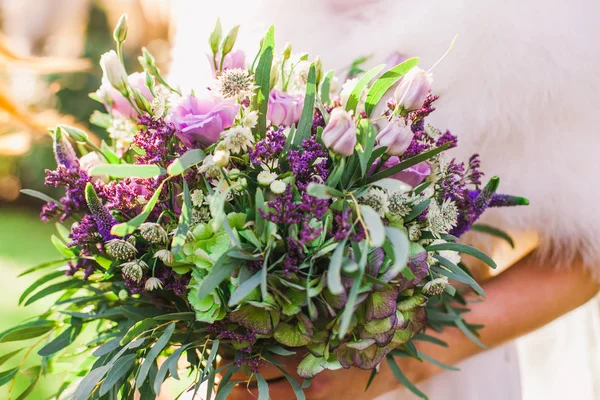 Beau bouquet de mariage violet entre les mains de la mariée — Photo