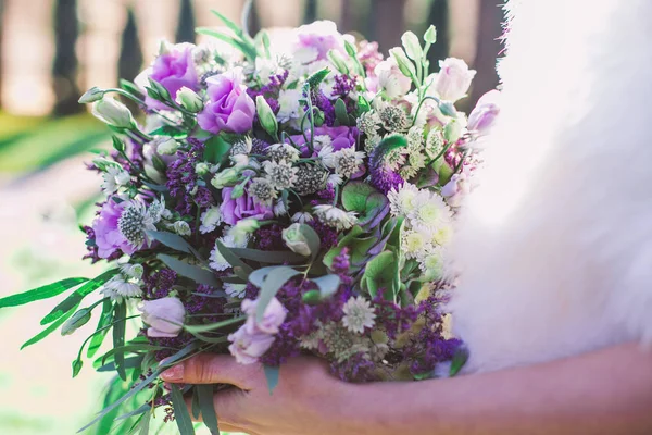 Vackert lila bröllop bukett i brudens händer — Stockfoto