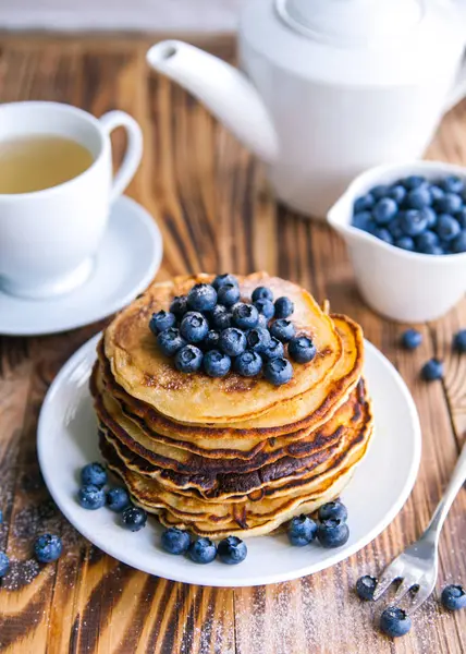 Yaban mersini, bataklık whortleberry, yeşil çay, yaban mersini ve çaydanlık kahverengi ahşap zemin üzerinde kupa ile sağlıklı kahvaltı krep 